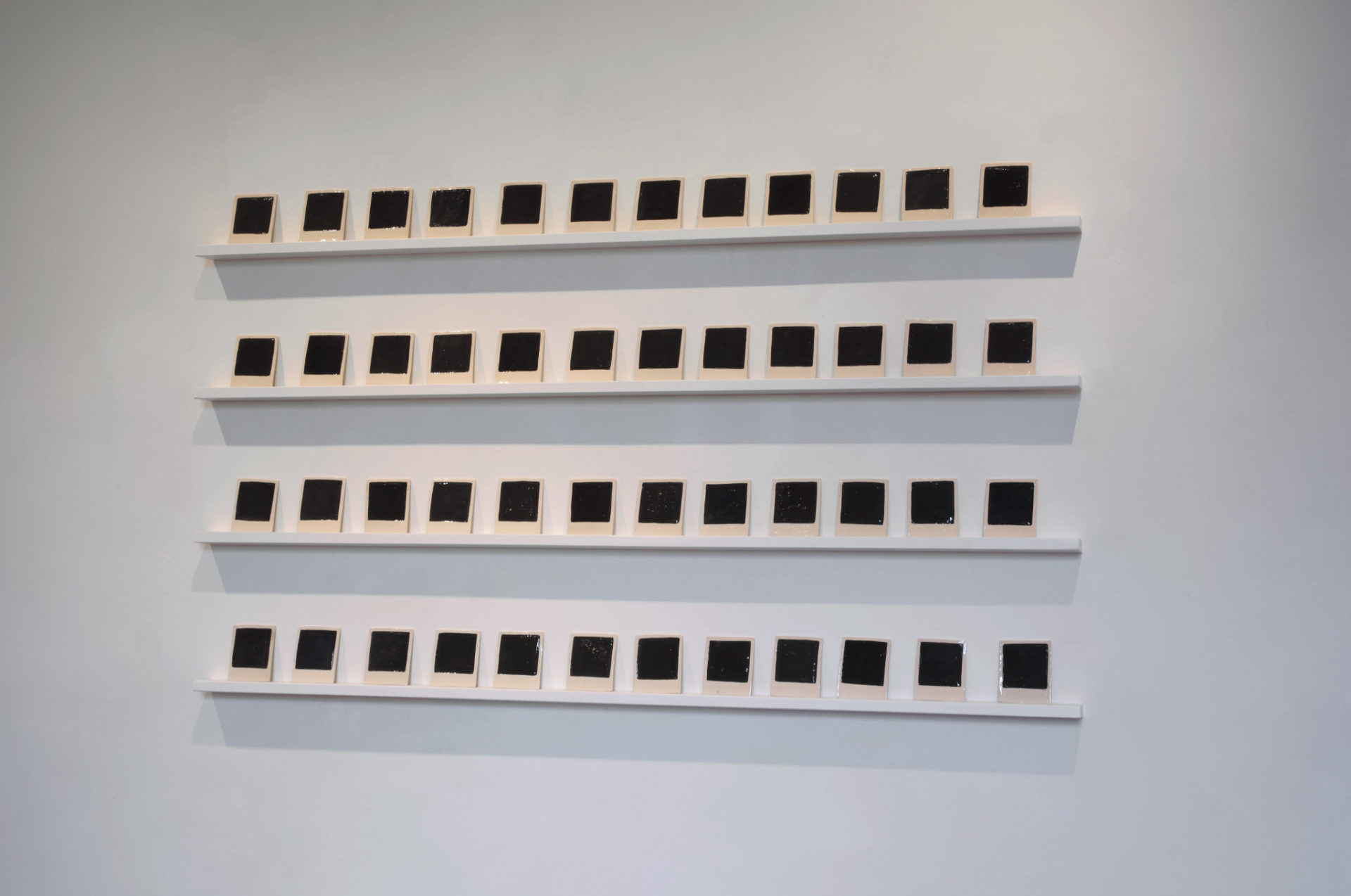 Polaroids, 48 glazed ceramic elements, 8,8x10,7 cm each, wooden shelves
